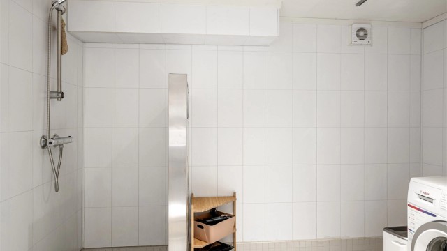 Innredet med vask, vegghengt toalett, dusjnisje og opplegg til vaskemaskin.