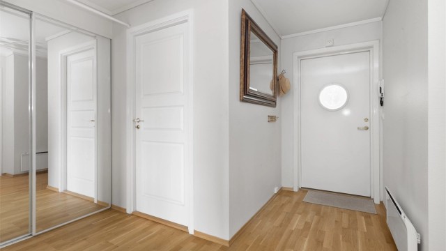 Gangen har parkett på gulv og god plass til oppbevaring i skyvedørsgarderobe. Bygget har heis og porttelefon.