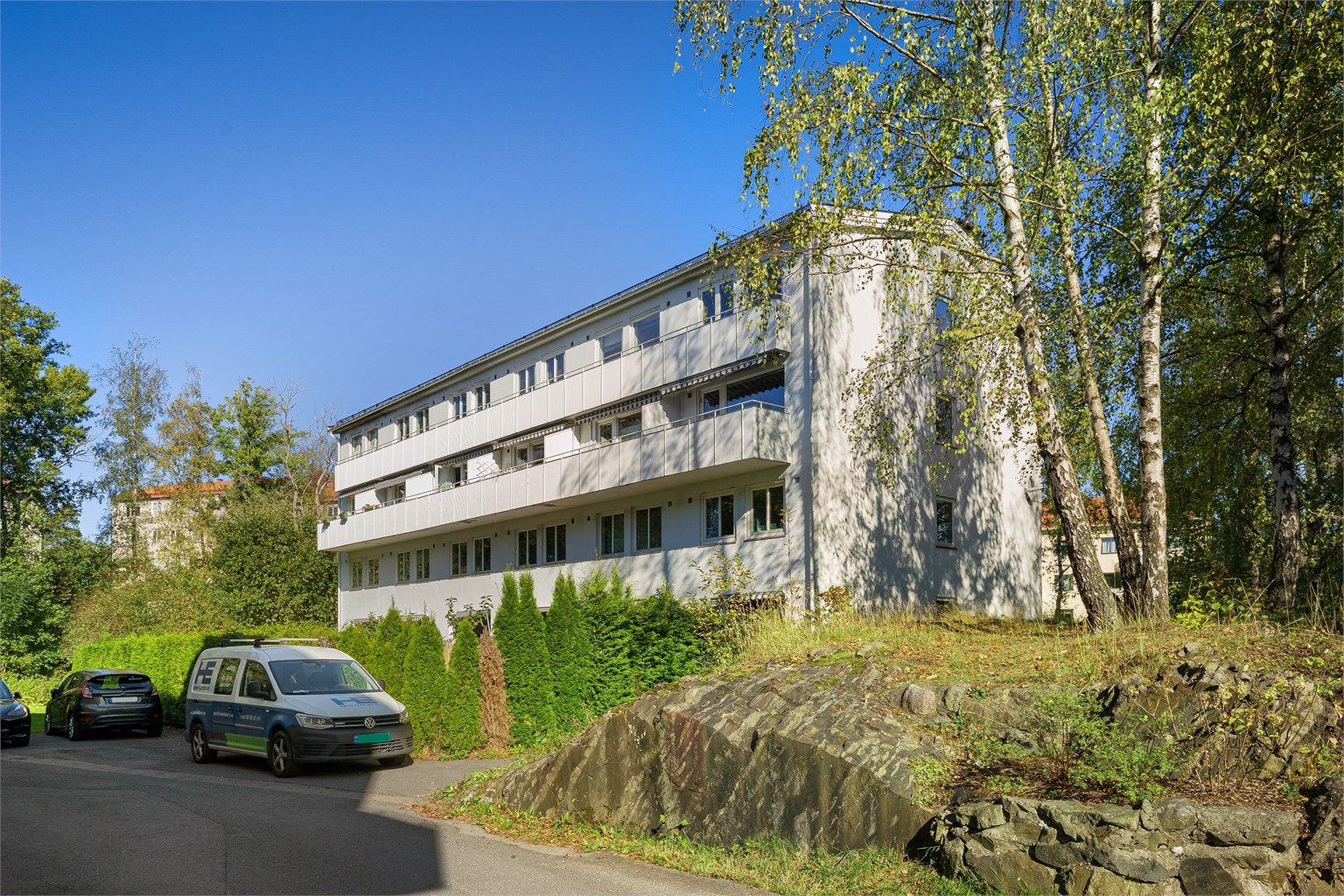 Bygget har en funksjonell arkitektur og er omgitt av grøntarealer.