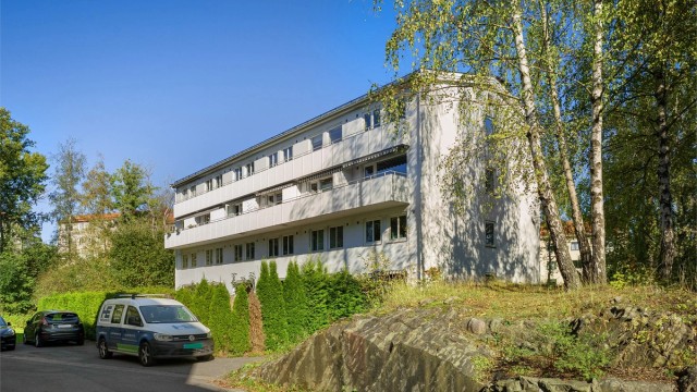 Bygget har en funksjonell arkitektur og er omgitt av grøntarealer.