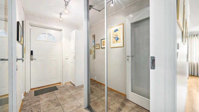Entré med flislagt gulv og skyvedørsgarderobe med speilfronter.