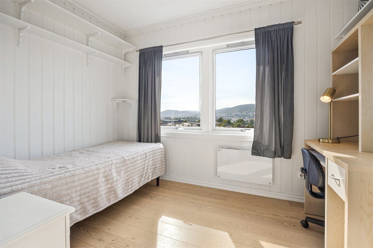 Lyst og trivelig soverom med praktiske, veggmonterte hyller.