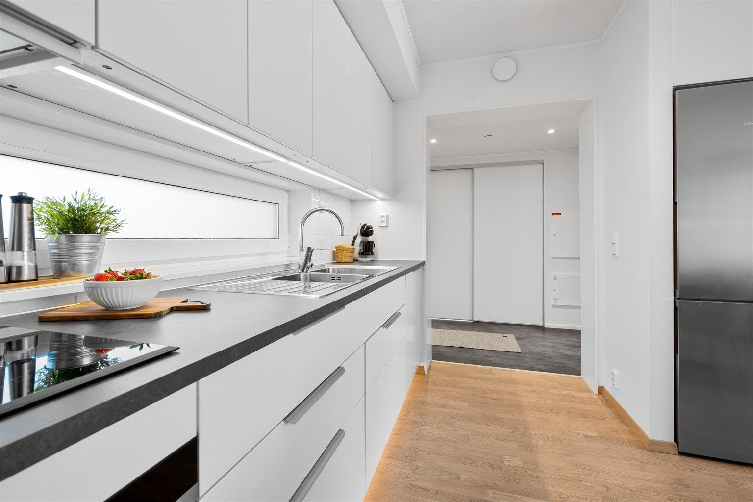 Kjøkkeninnredning fra byggeår med stilrene, slette fronter og praktisk laminat benkeplate.