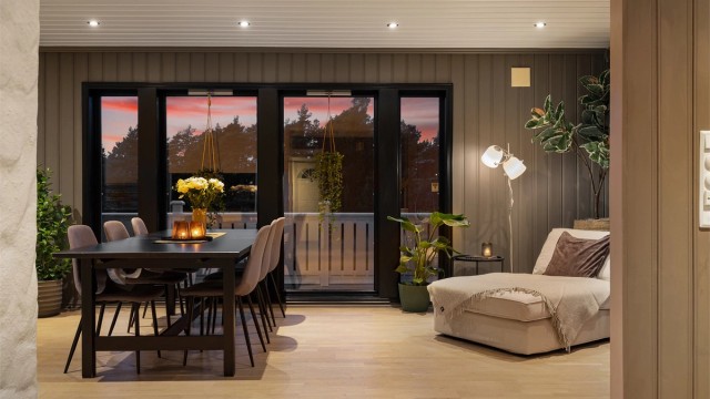 Vertikalstilte vinduer i både syd- og vestveggen fyller stuen med naturlig lys hele dagen.