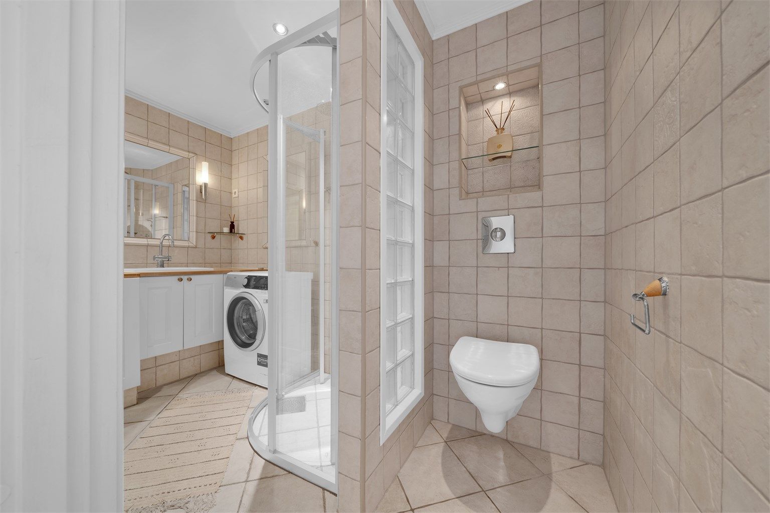 Vegghengt toalett med innebygget sisterne og downlights i himling.