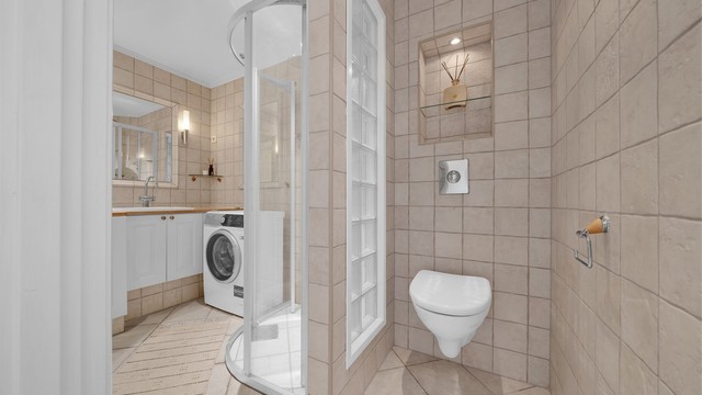 Vegghengt toalett med innebygget sisterne og downlights i himling.