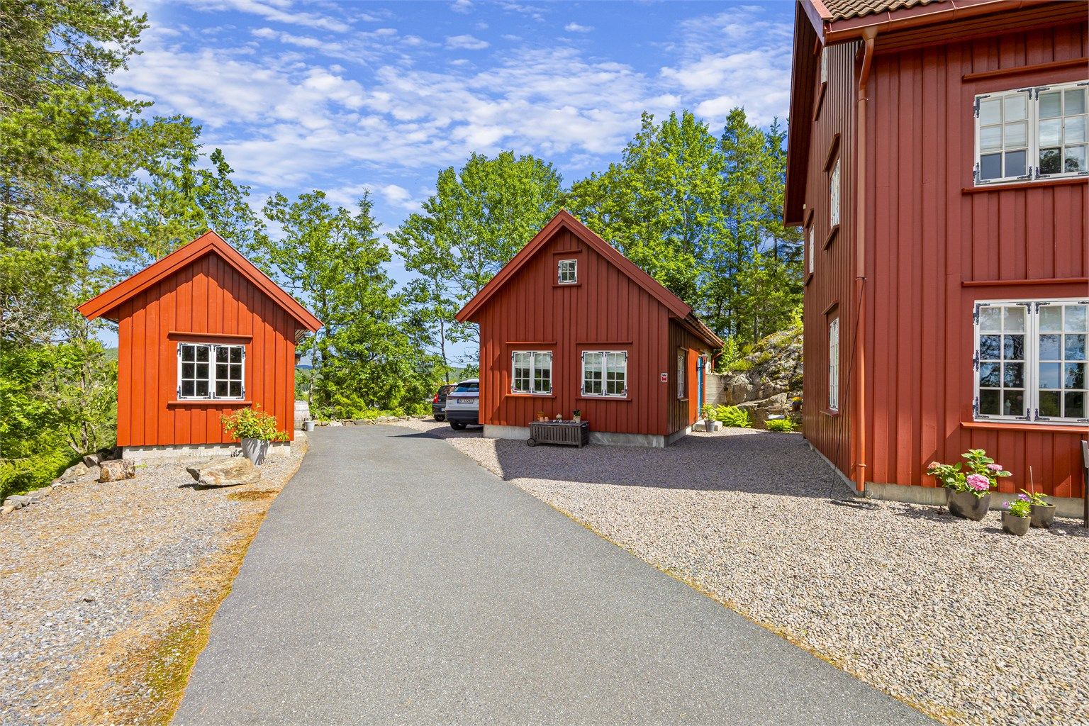 Asfaltert adkomstvei fører opp til boligen, verkstedet og redskapsboden.
