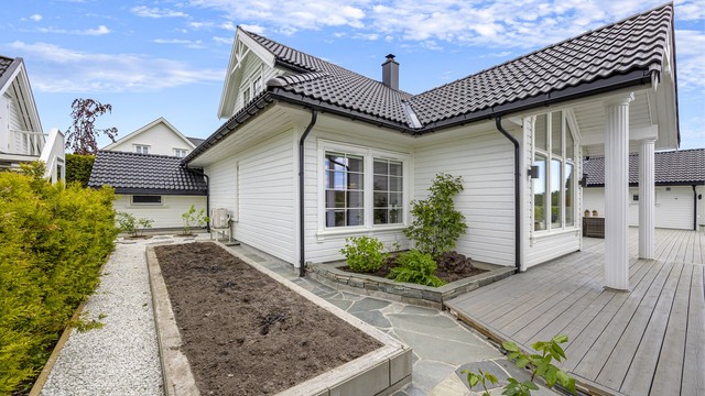 Tomten er pent opparbeidet med skifer, beplantning og en egen kjøkkenhage.
