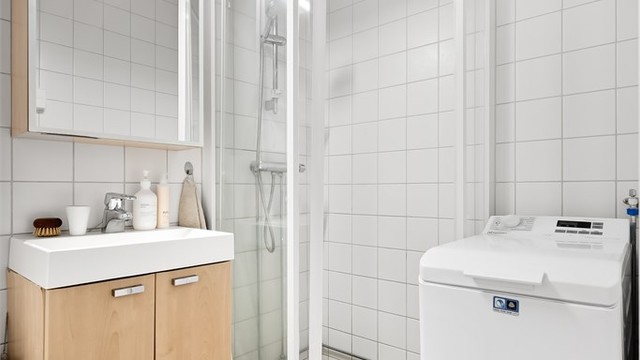 Rommet er innredet med dusjhjørne, servantmøbel og opplegg for vaskemaskin.