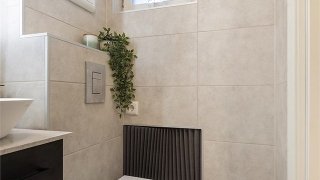 Badet har vegghengt toalett med innebygd sisterne. Fordelerskapet for rør-i-rør-systemet er plassert på veggen.