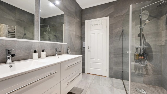 Badet er innredet med 2 nedfelte servanter, veggmontert toalett og dusjvegger/hjørne.