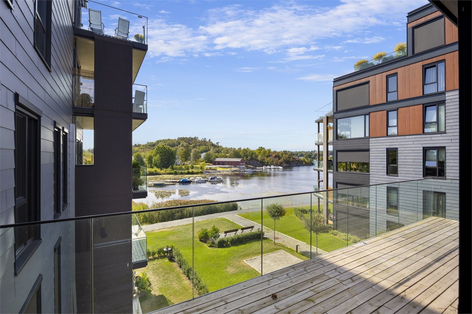Balkongen er belagt med terrassebord og har rekkverk i glass for fri sikt.