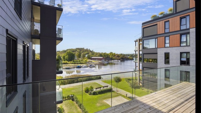Balkongen er belagt med terrassebord og har rekkverk i glass for fri sikt.