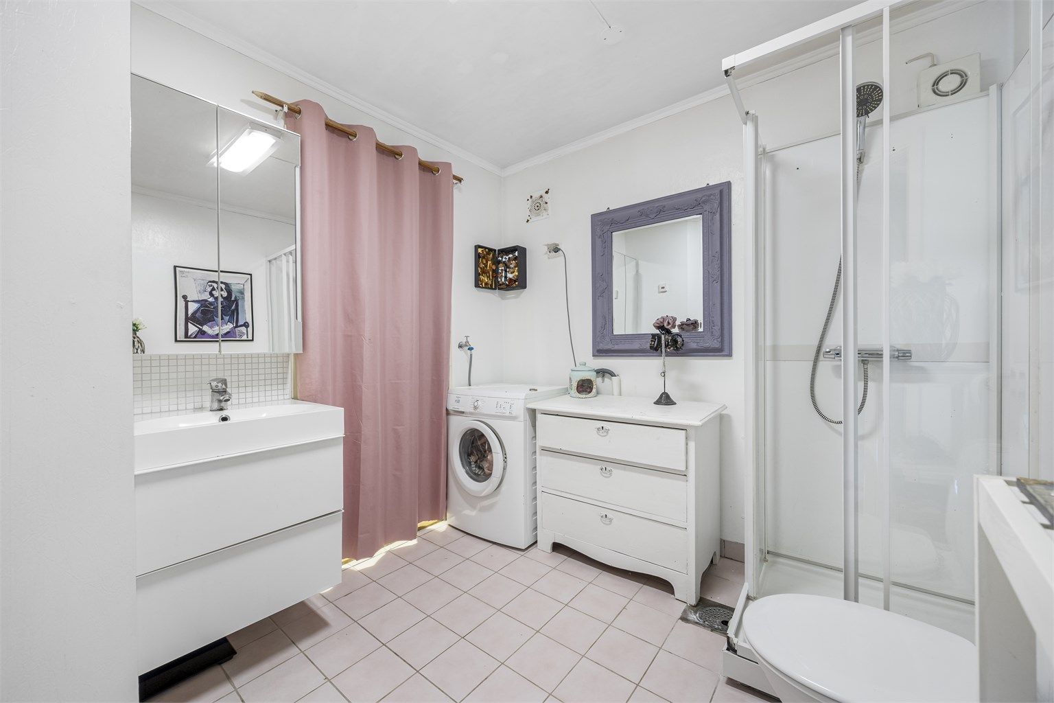 Badet er utstyrt med flislagt gulv med varmekabler, dusjkabinett, gulvstående toalett og opplegg for vaskemaskin. 