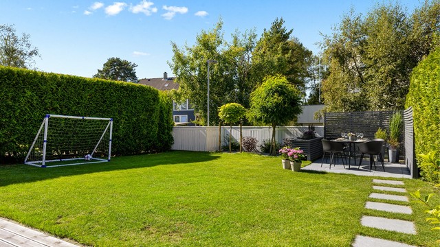Velstelt hage med plen og diverse beplantninger.