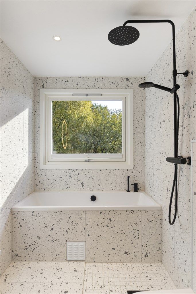 Badet er utstyrt med innmurt badekar med innebygget armatur samt vegghengt regndusj og hånddusj.