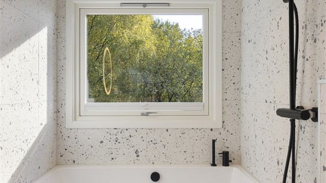 Badet er utstyrt med innmurt badekar med innebygget armatur samt vegghengt regndusj og hånddusj.