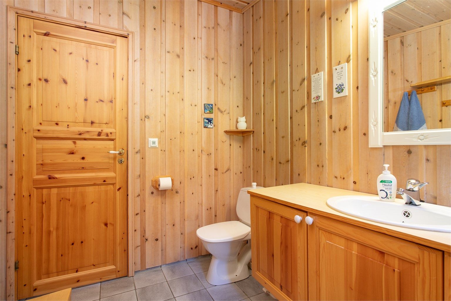 Badet har dusjhjørne og panel på veggene utenfor dusjsonen.