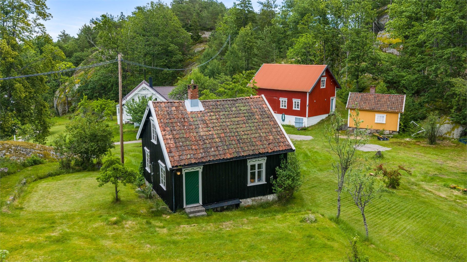 Gjestehuset i front av bildet er fullt av karakter -  og inngår i et helhetlig tun med plass til familie, venner og rolige sommerdager