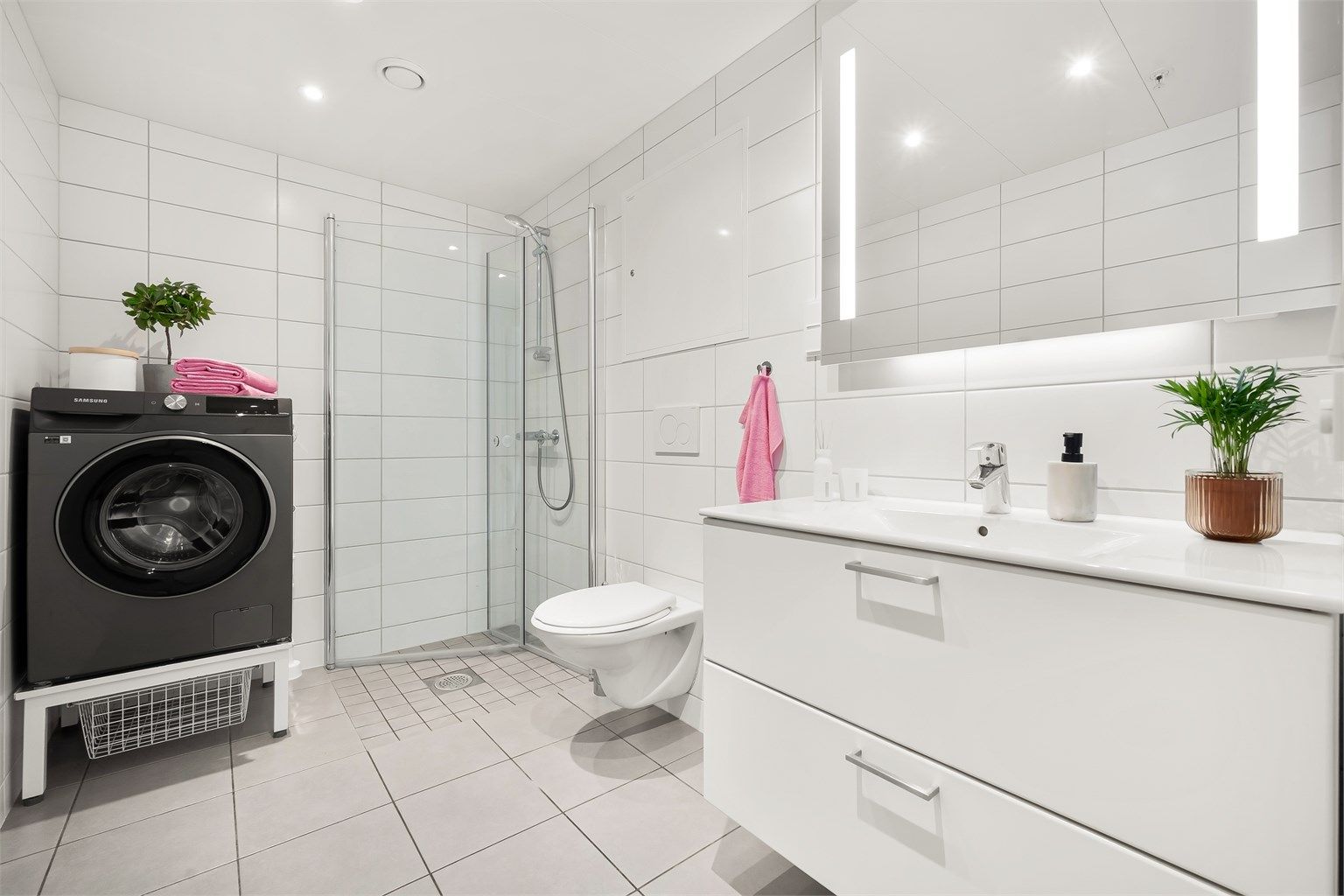 Badet er innredet med vegghengt klosett, servant nedfelt i moderne innredning, speilskap med belysning og dusjhjørne med svingbare glassdører.