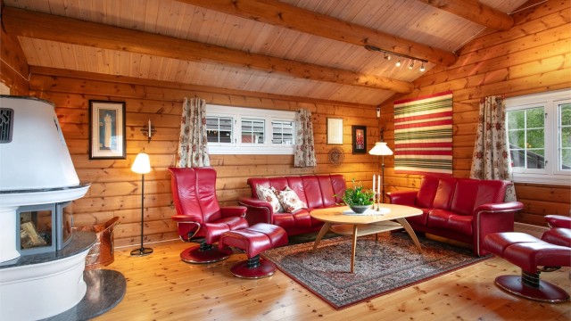 En innholdsrik fritidsbolig i laftet tømmer fra 2010, med en sentralt plassert peis.
Foto: Jarle Osen