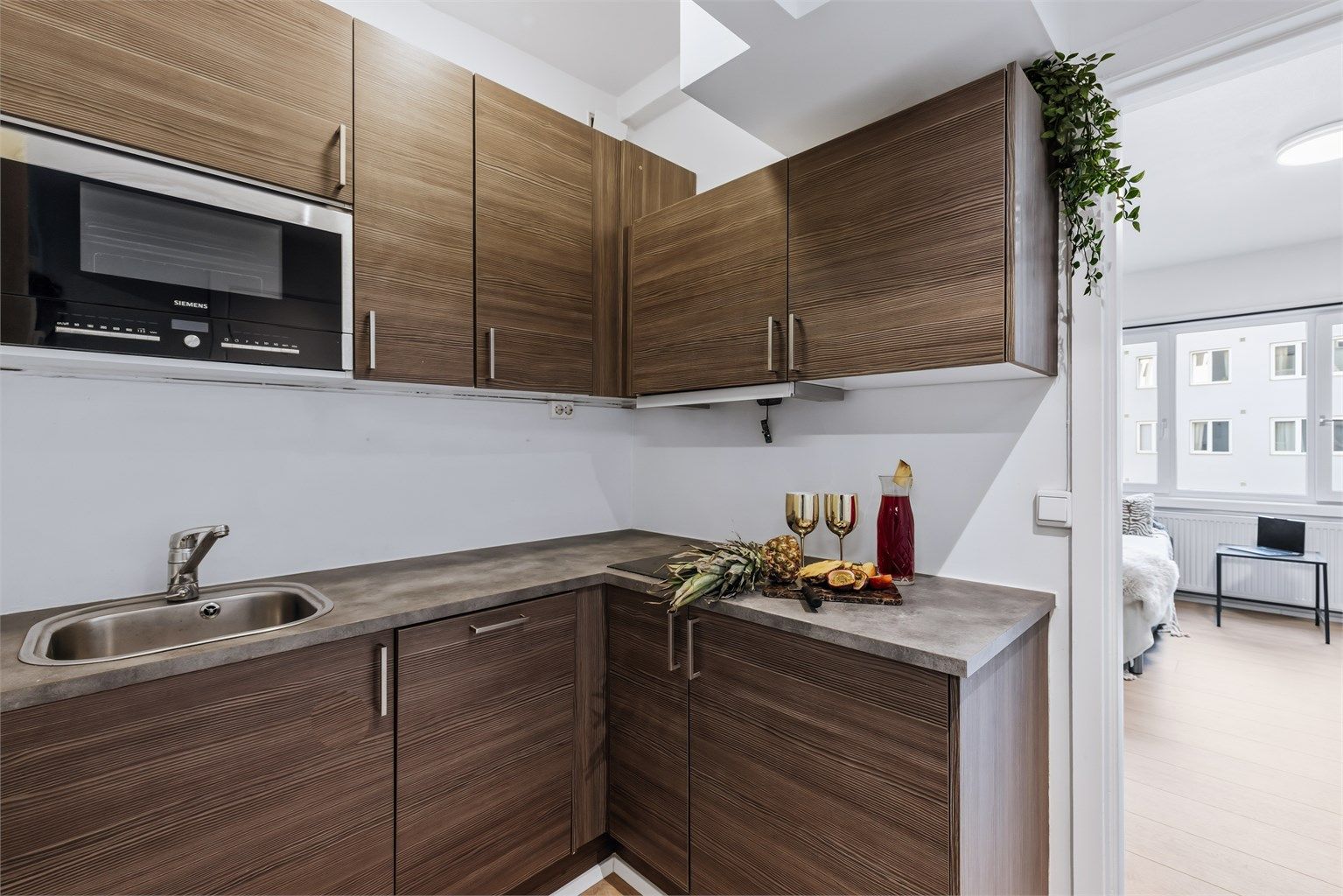 Praktisk kjøkken med innredning bestående av glatte fronter, benkeplate med laminert overflate og nedfelt kjøkkenvask med armatur. Kjøkkenet er er utstyrt med integrert stekeovn med mikrobølgeovn, platetopp, oppvaskmaskin og kjøleskap.