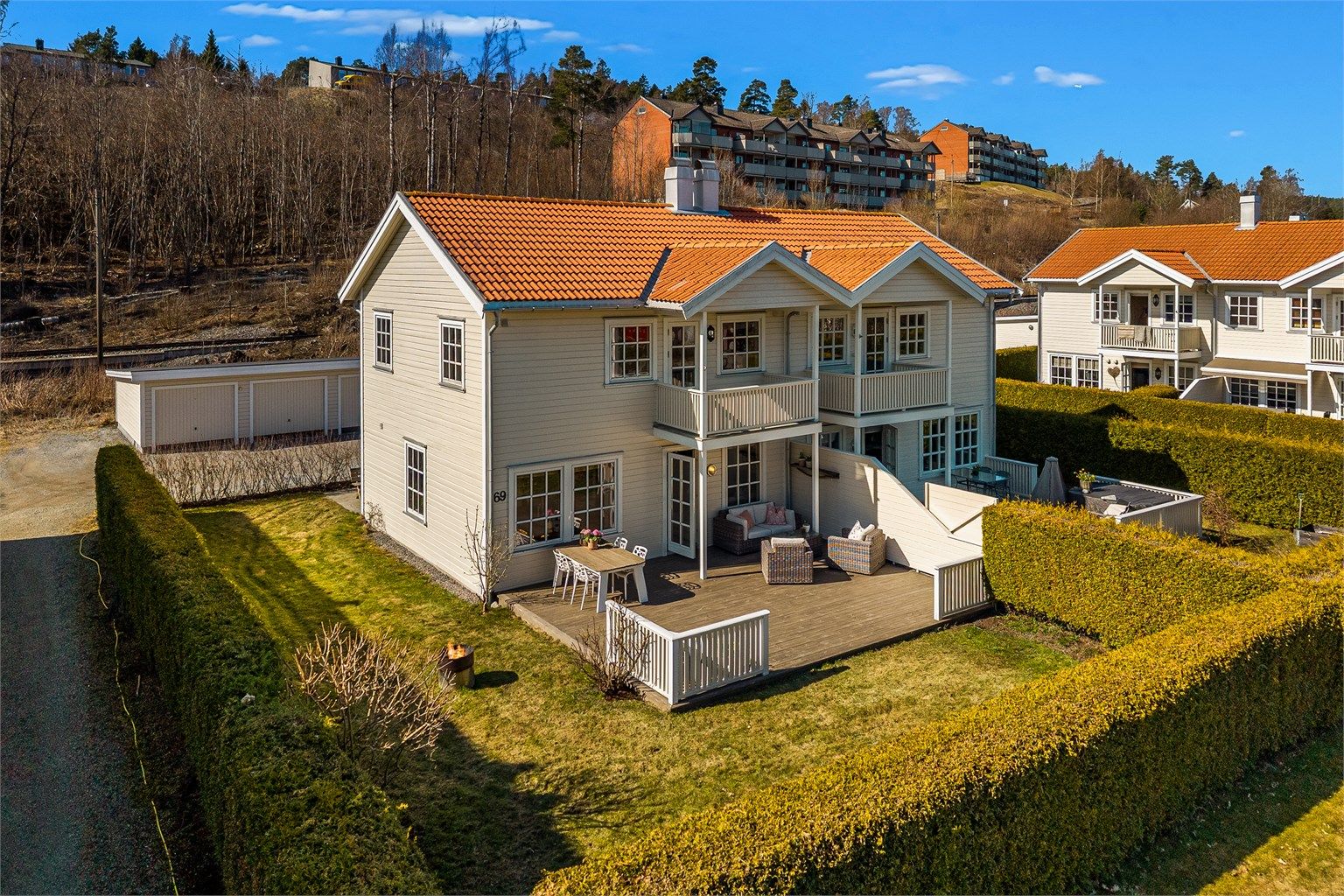 Usjenert hage med gressplen og stor terrasse er omkranset av hekk.