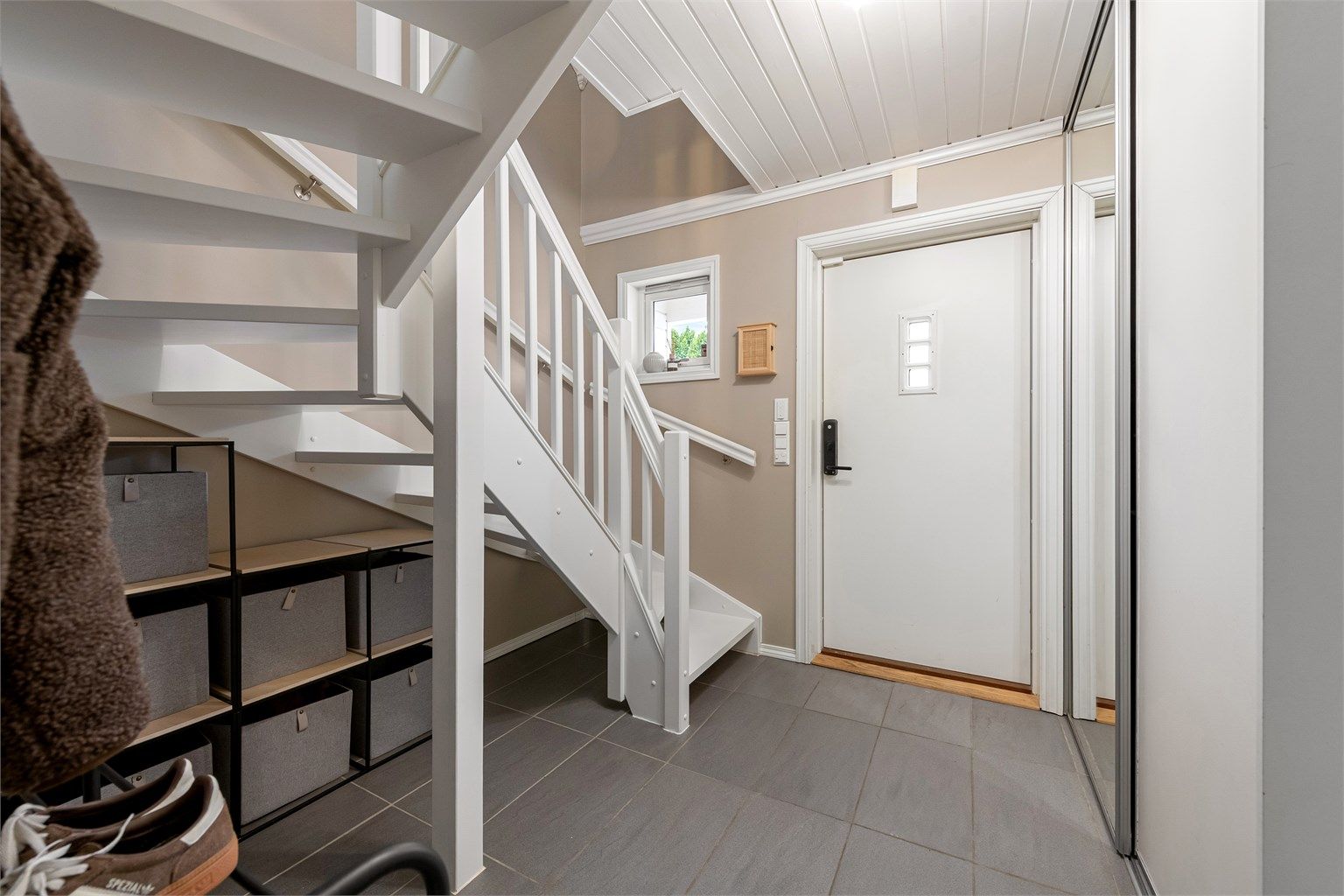 Entréen har flislagt gulv med gulvvarme og en stor skyvedørsgarderobe for effektiv oppbevaring.
