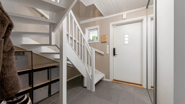 Entréen har flislagt gulv med gulvvarme og en stor skyvedørsgarderobe for effektiv oppbevaring.