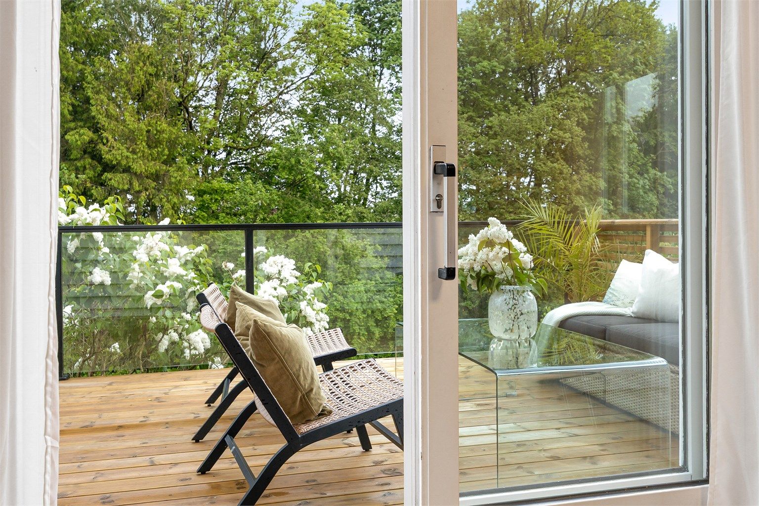 Verandaen i første etasje har rekkverk i tre, glass og metall.