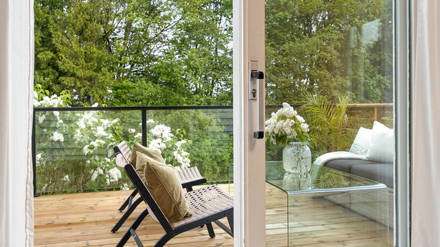 Verandaen i første etasje har rekkverk i tre, glass og metall.