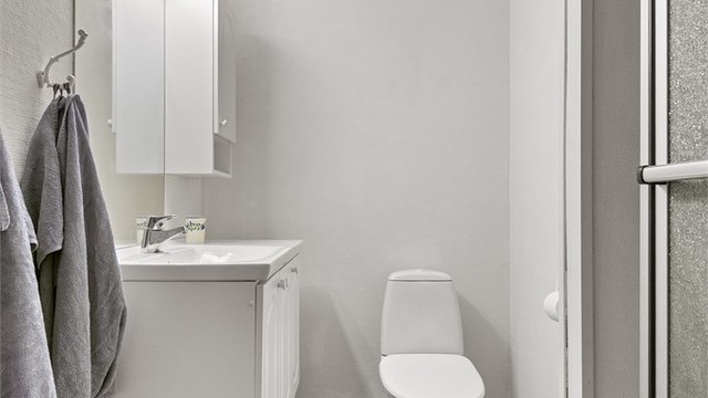 Badet har gulvvarme og servant med oppbevaring.