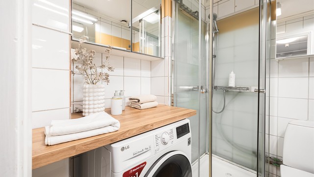 Videre er det speilskap på vegg over benkeplaten i tre som fungerer godt som en brettestasjon etter at klesvasken er tatt. Opplegg for vaskemaskin.