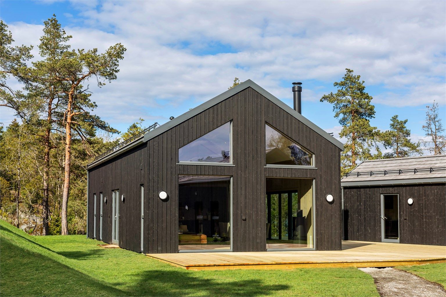 Hytta som er omgitt av natur glir fint inn med kledning og takstein som står fint sammen.