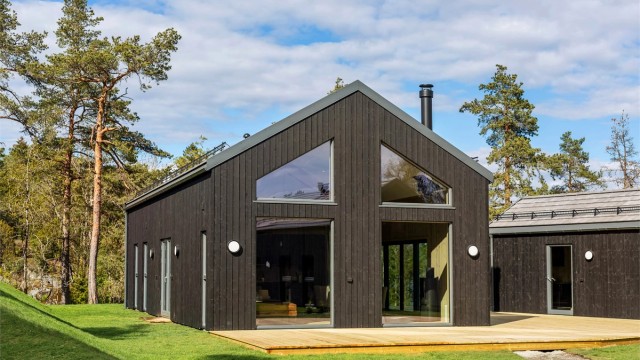 Hytta som er omgitt av natur glir fint inn med kledning og takstein som står fint sammen.