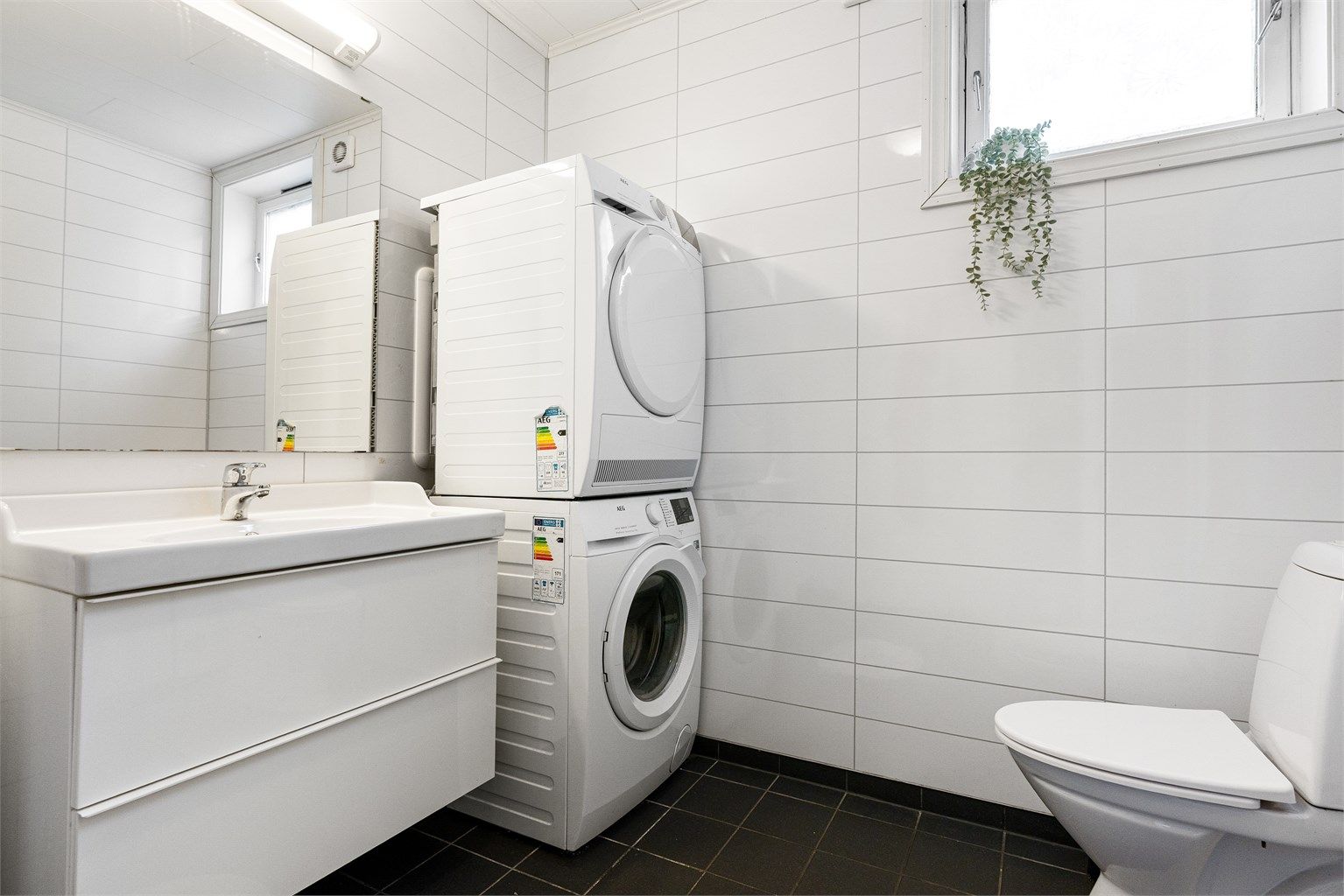 Badet har flislagt gulv med varme og baderomsplater på vegg samt opplegg for vaskemaskin og tørketrommel. 