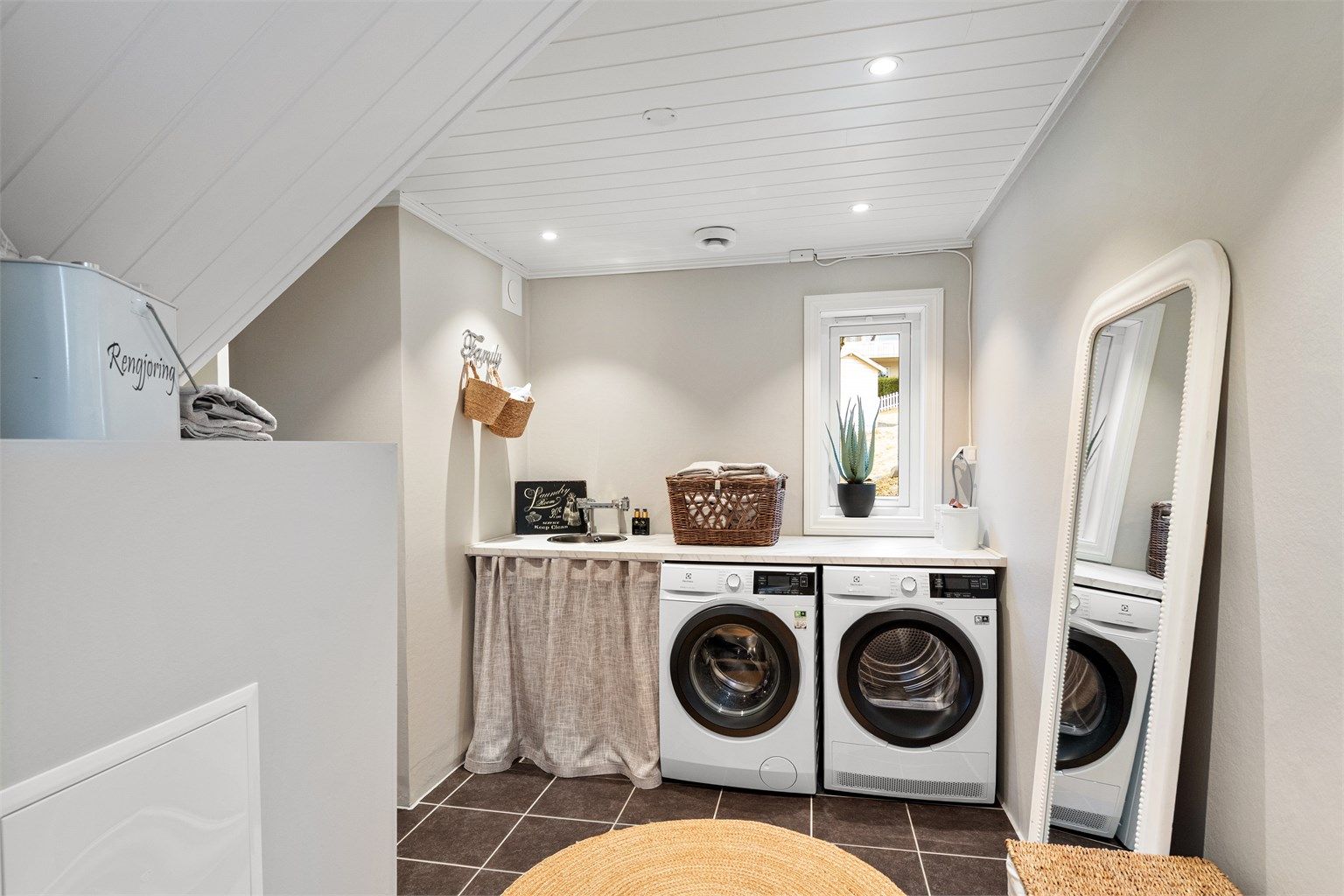 Separat vaskerom med opplegg for vaskemaskin og tørketrommel under en praktisk benkeplate