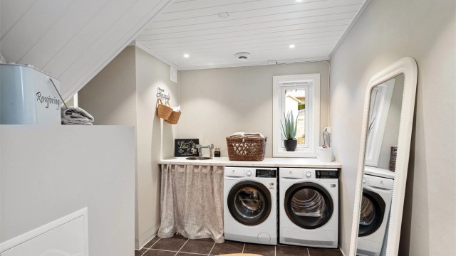 Separat vaskerom med opplegg for vaskemaskin og tørketrommel under en praktisk benkeplate