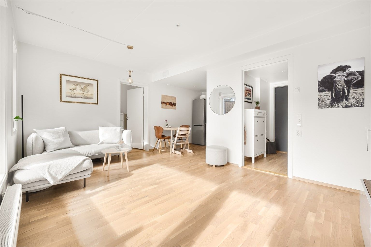 Leiligheten har en åpen stue- og kjøkkenløsning, hvor kjøkkenet er naturlig avskjermet og danner en egen, stilren sone. Foto: Martine Eren Studio