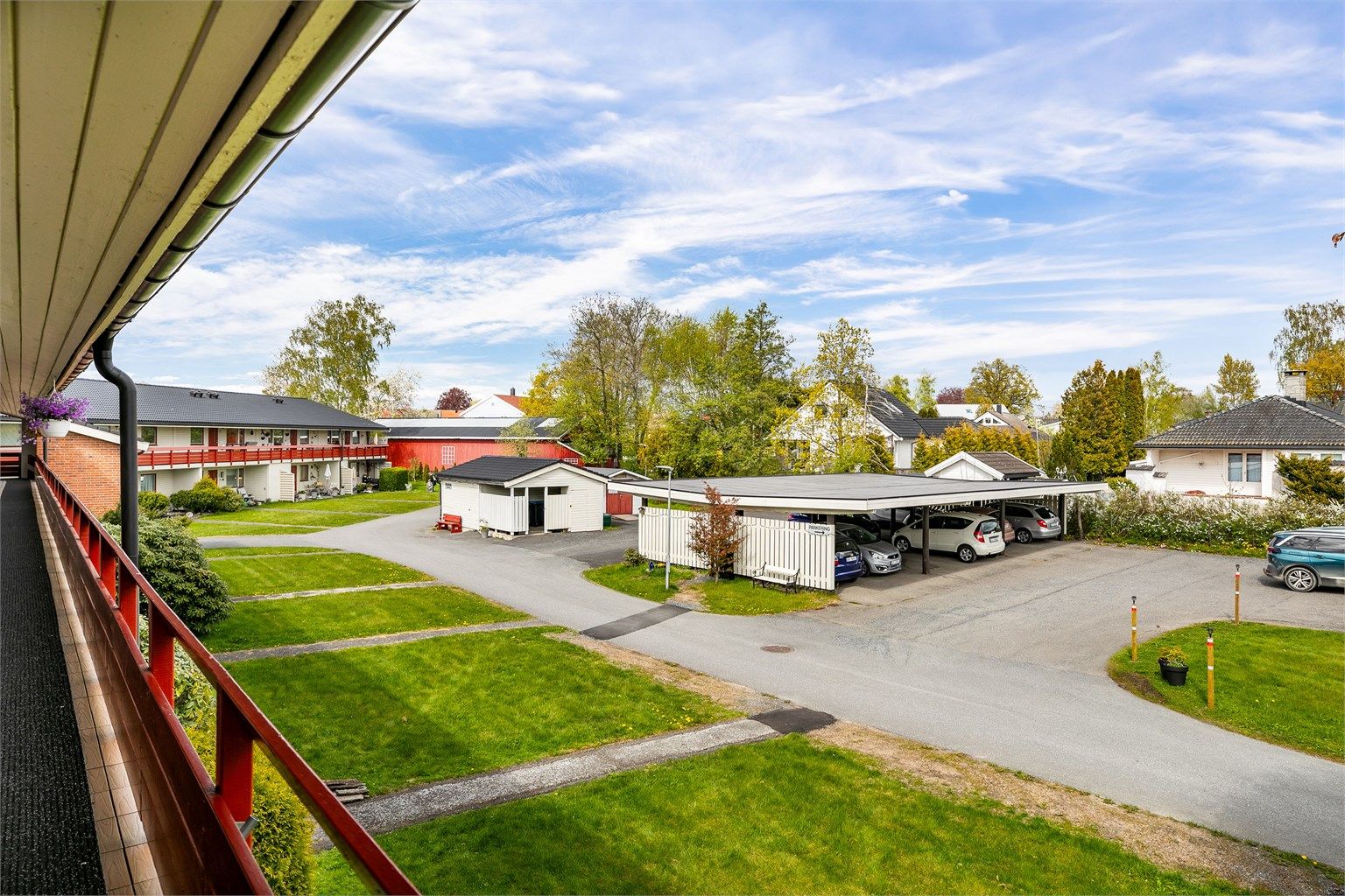 Utsyn fra svalgangen til fellesarealet der leiligheten disponerer biloppstillingsplass. Ved plassen er det montert ladepunkt som medfølger.