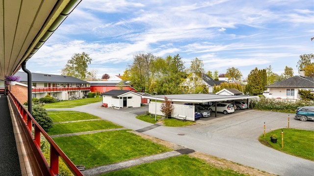 Utsyn fra svalgangen til fellesarealet der leiligheten disponerer biloppstillingsplass. Ved plassen er det montert ladepunkt som medfølger.