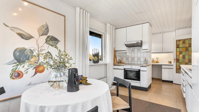 Kjøkken av ukjent alder med slette fronter og frittstående hvitevarer.