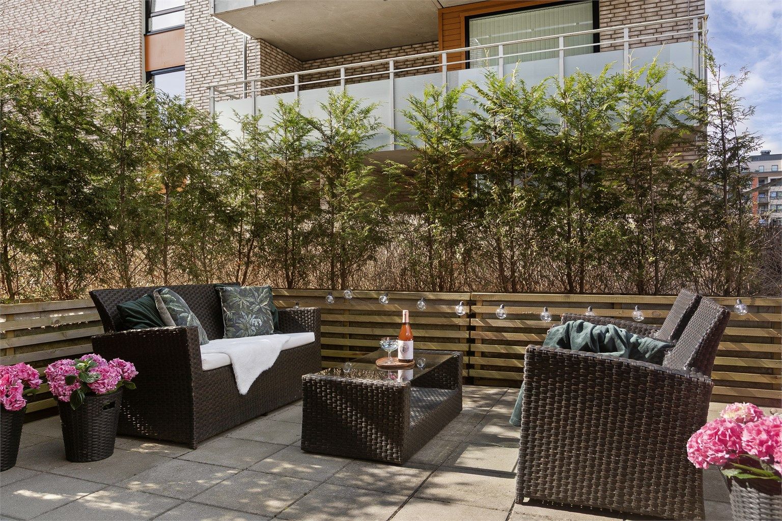 Stor usjenert markterrasse som er fint skjermet med plantekasser og busker - Foto: Eiendomsfoto 