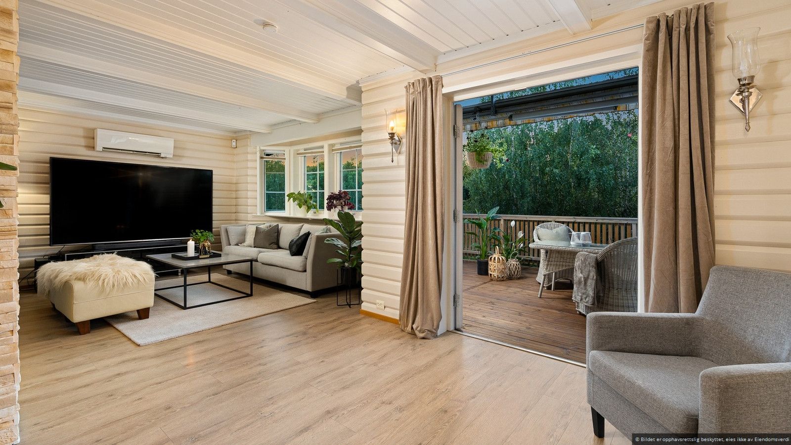 Hyggelig stue med utgang til veranda som omkranser boligen.