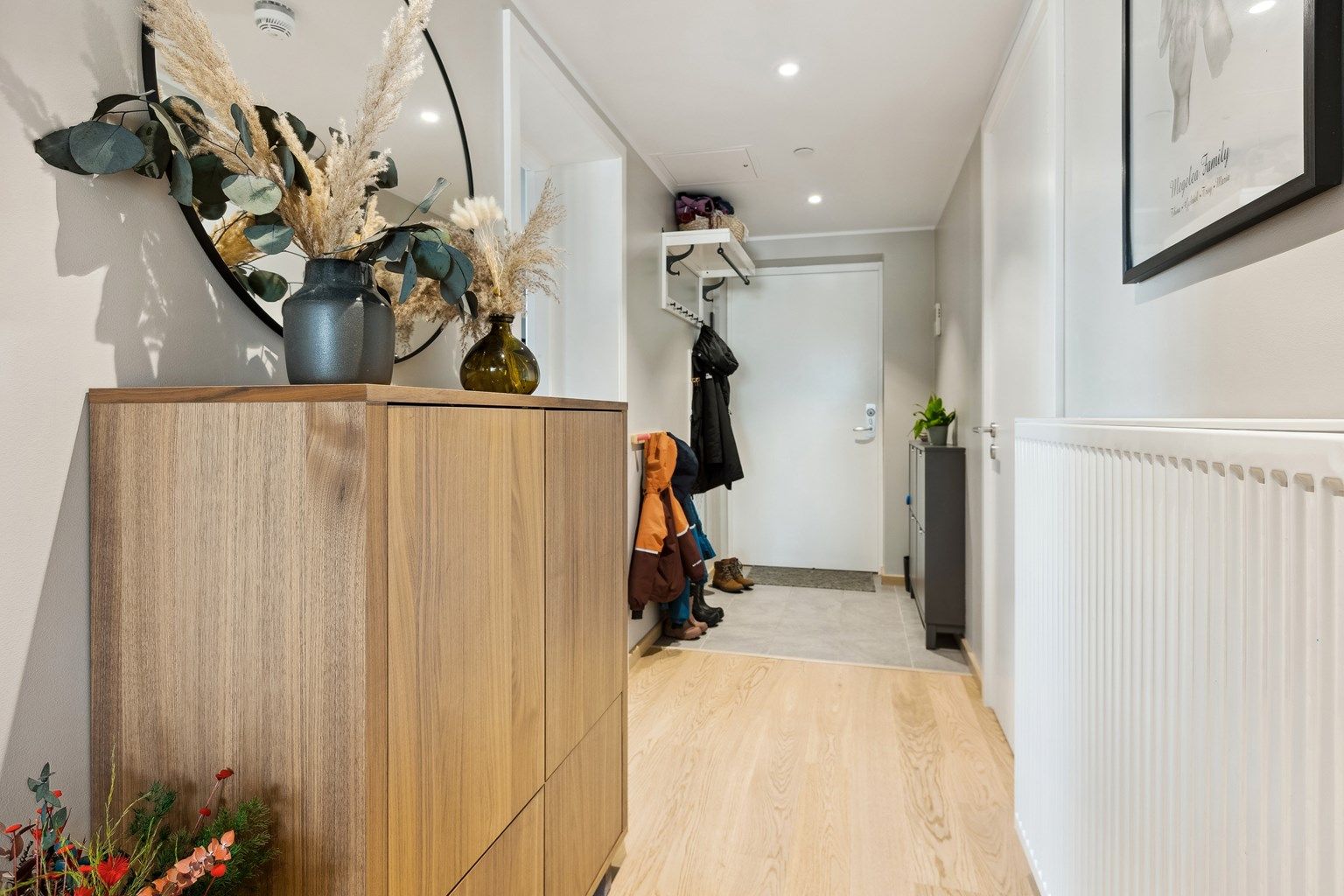 Velkommen inn i lys og pen entré med flislagte gulv med varme, lysemalte vegger og downlights i himling