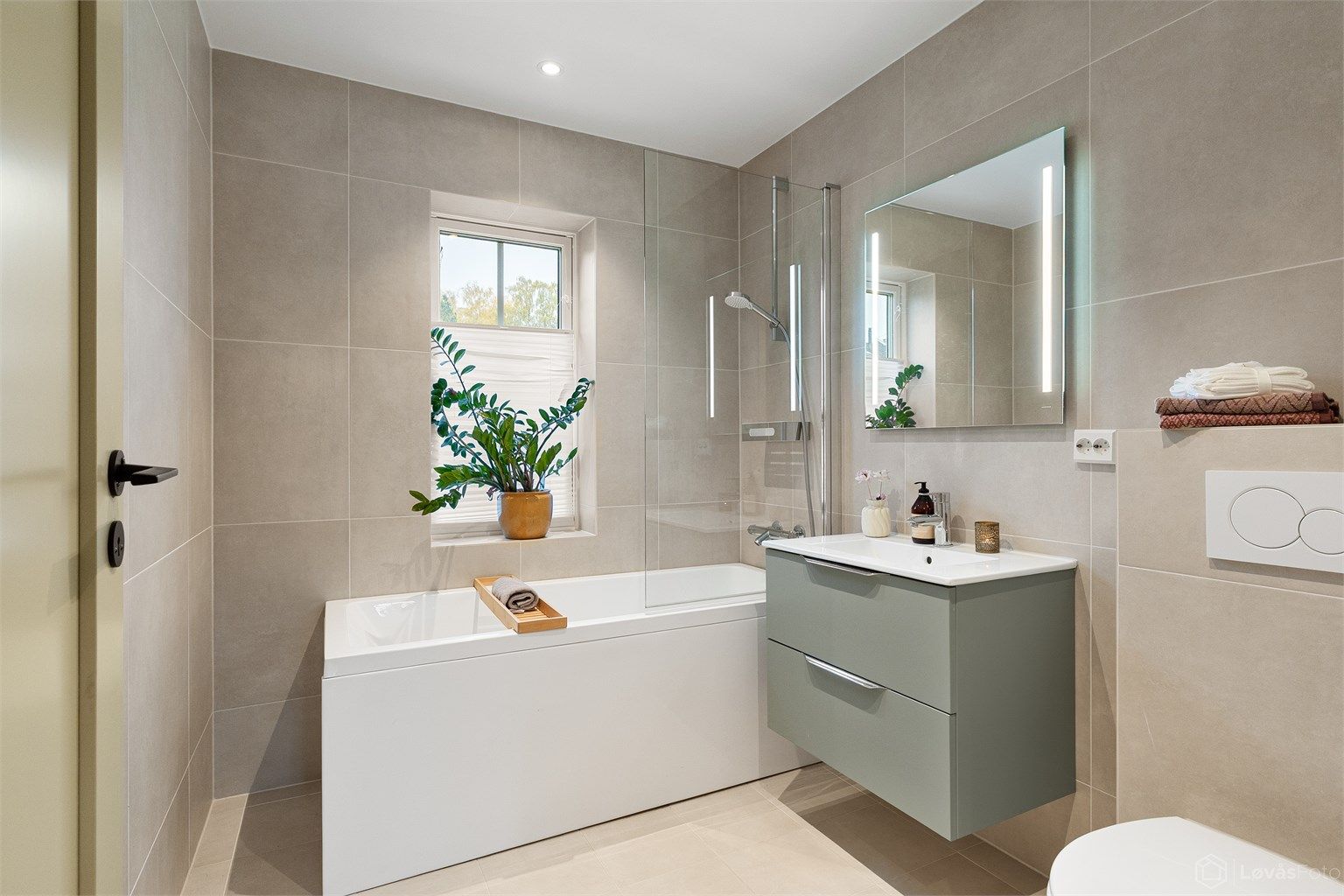 Badet ved trappen er innredet med badekar, dusjvegg i glass og gulvvarme.