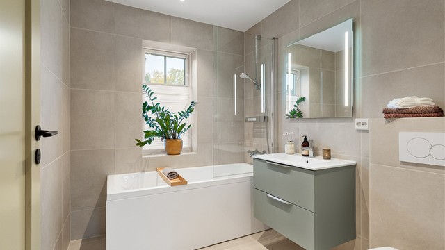 Badet ved trappen er innredet med badekar, dusjvegg i glass og gulvvarme.