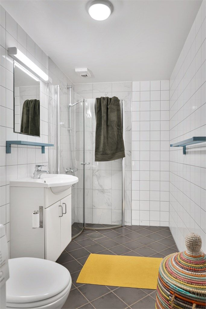 Gulvstående toalett, servant med skapinnredning under og vegghengt speil med belysning over
