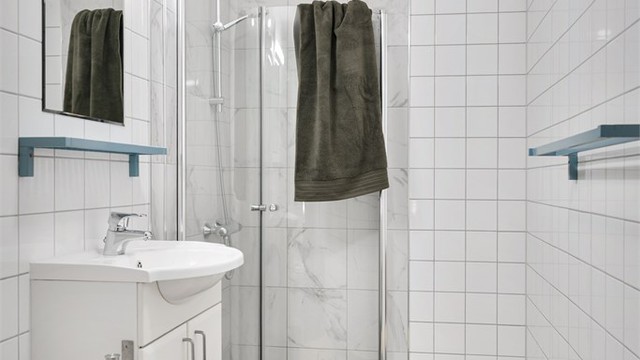 Gulvstående toalett, servant med skapinnredning under og vegghengt speil med belysning over