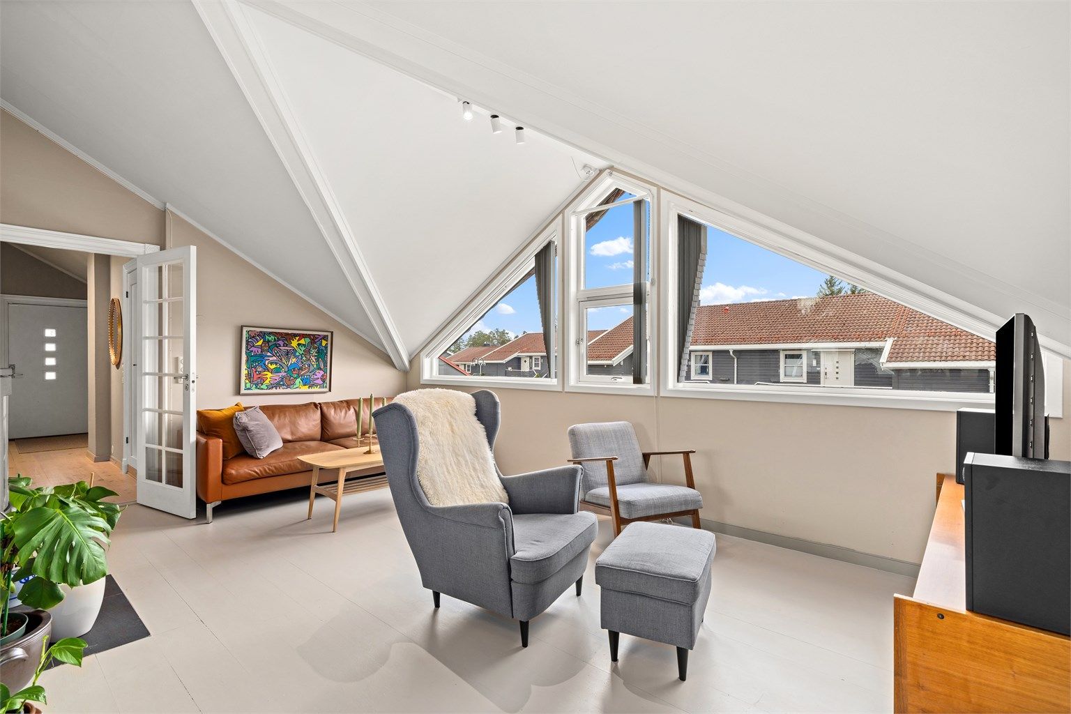 Stuen har en åpen løsning mot kjøkkenet, og de store, karakteristiske vindusflatene gir rikelig med dagslys.